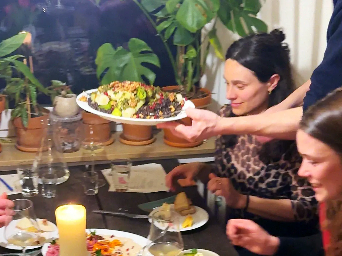 Ein Teller mit warmem Essen wird über den gedeckten Tisch gereicht