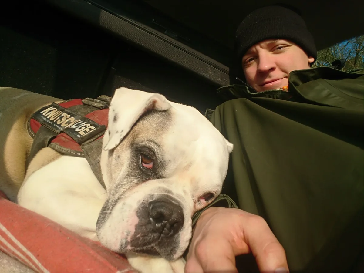 Ich mit Mütze im Auto, Abby liegt neben mir, den Kopf auf meinem Arm